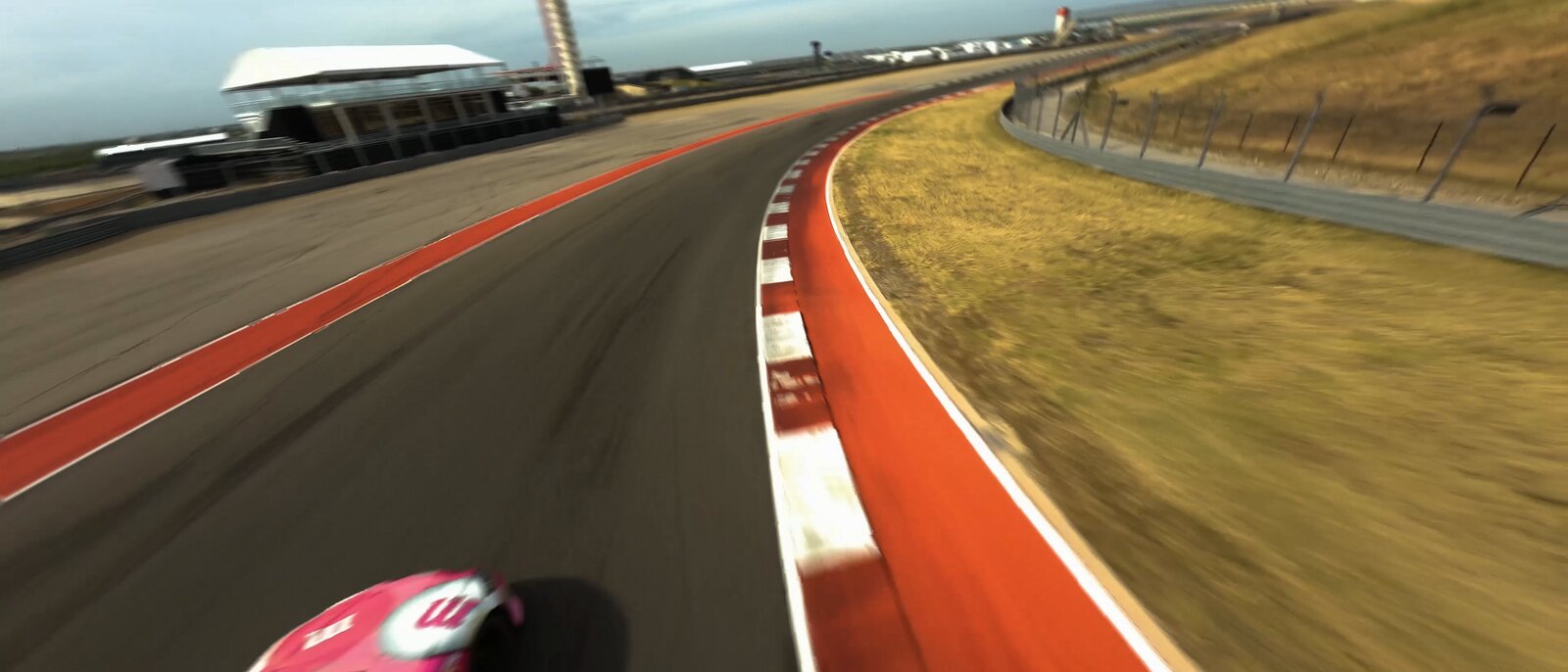 FPV chase frame over the race circuit — aerial still from the Woodson reel